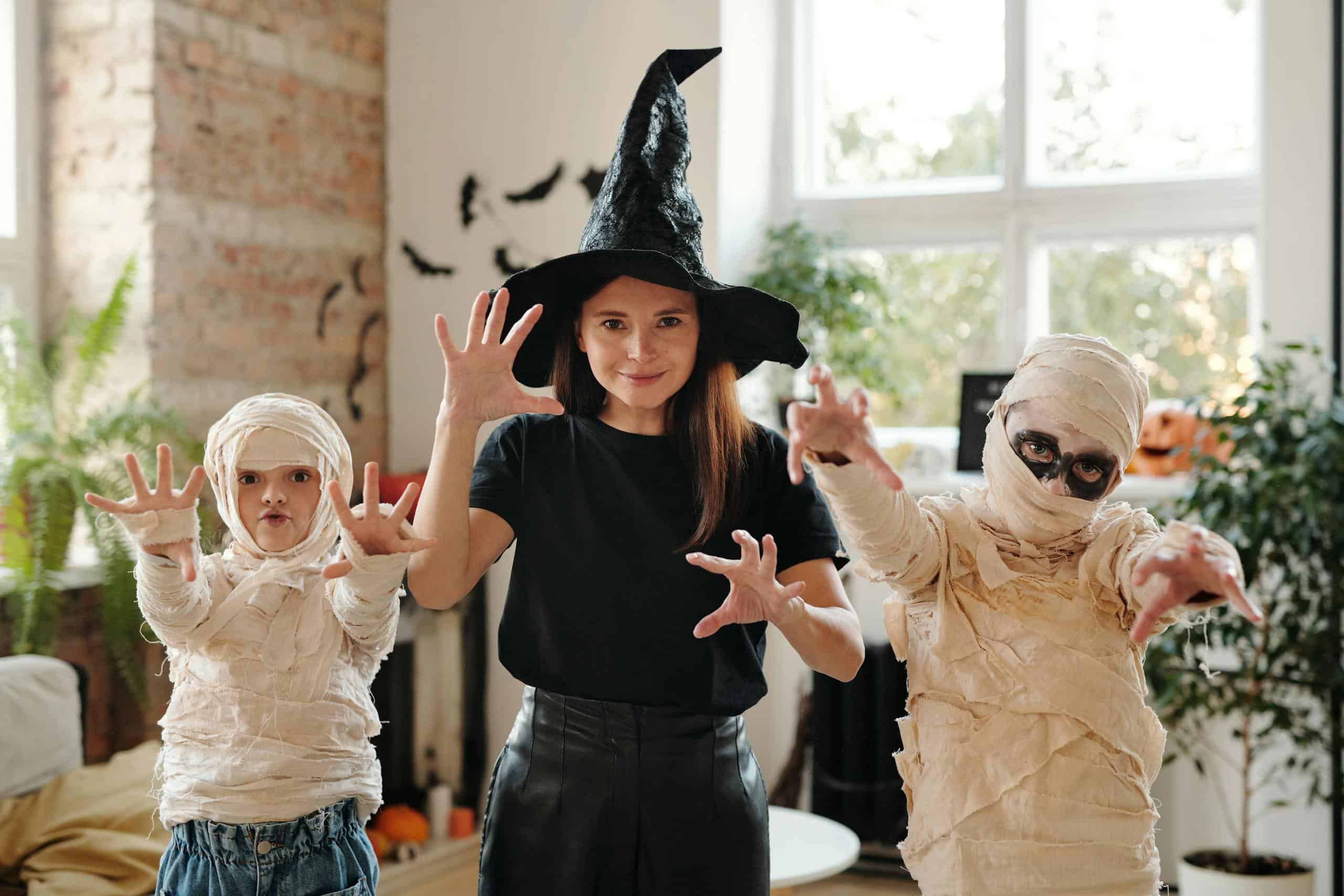 Family joyfully dressed in spooky Halloween costumes indoors, celebrating the holiday together.