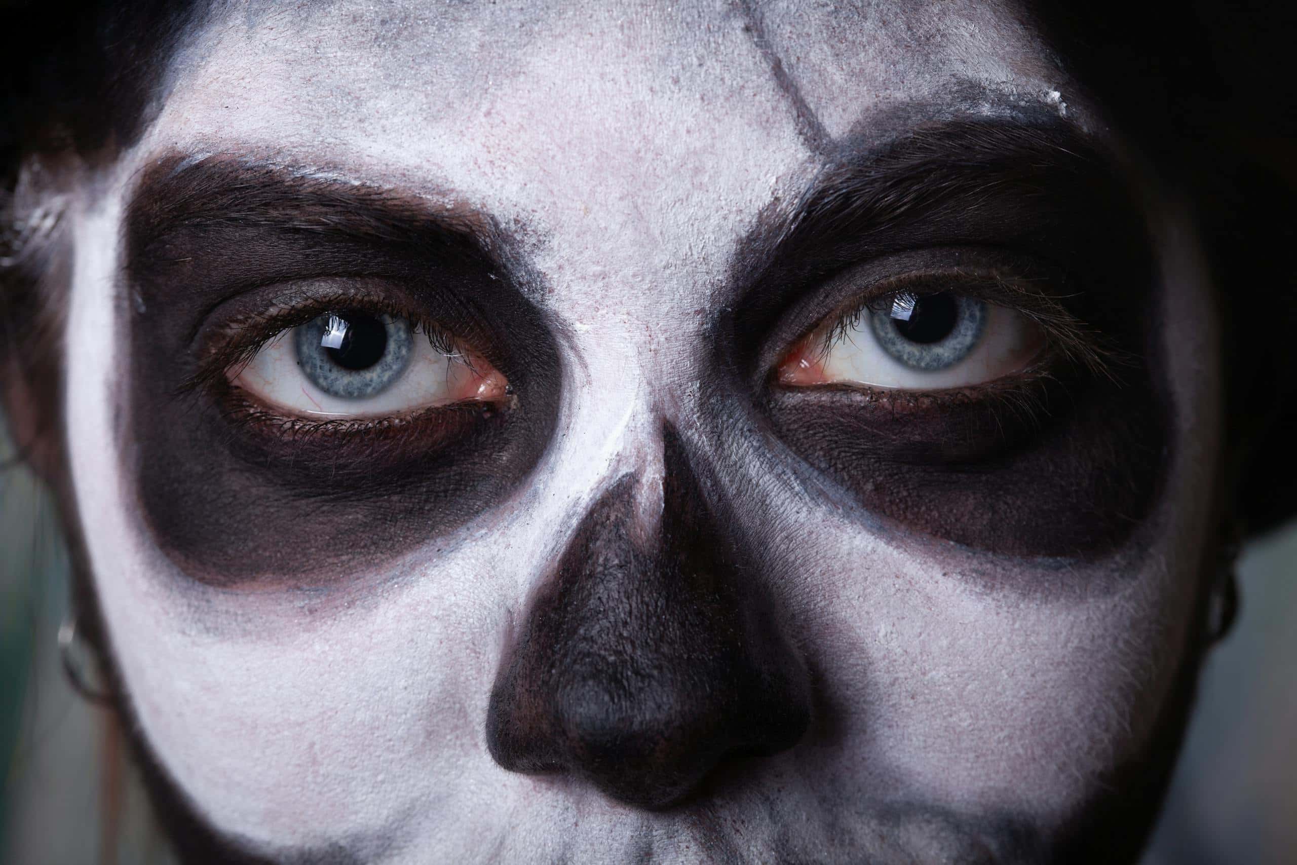 Intense close-up of a face painted with spooky Halloween skull makeup, featuring haunting eyes.